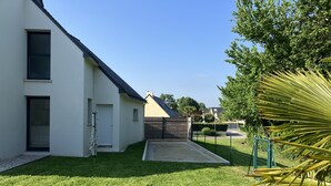A modern house with a white exterior, a dark roof, and a well-maintained lawn. - House near the sea (500 m) (Le Tour-du-Parc)