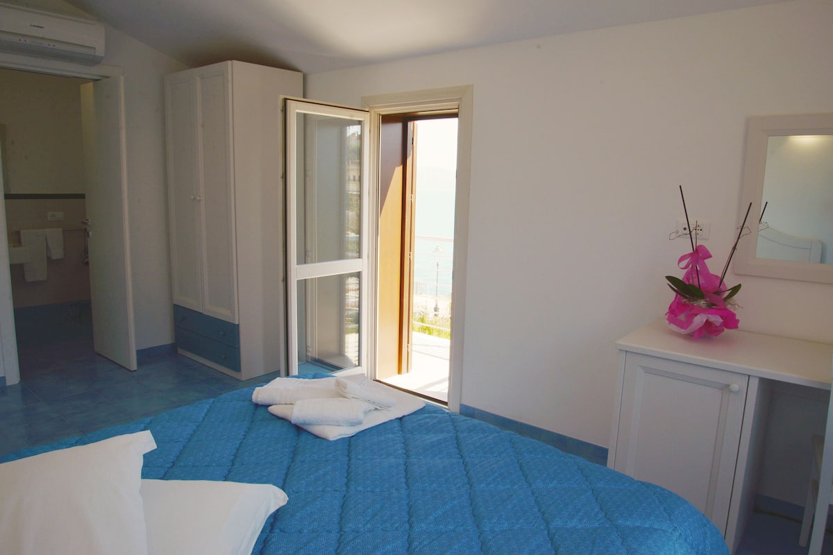 A bedroom with a bed, a bathroom, and a view through an open door.