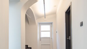 A hallway with a carpeted floor, white walls, and a door at the end. - Cha Cha Rooms (Ljubljana)