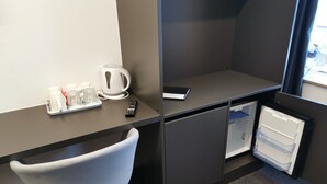 A compact hotel room with a kitchenette, a small fridge, a chair, and a window with a view. - Cha Cha Rooms (Ljubljana)