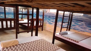 A room with two beds, wooden furniture, and a view of the ocean. - Bidi Badu Zanzibar Village - Hostel (Diani Beach)