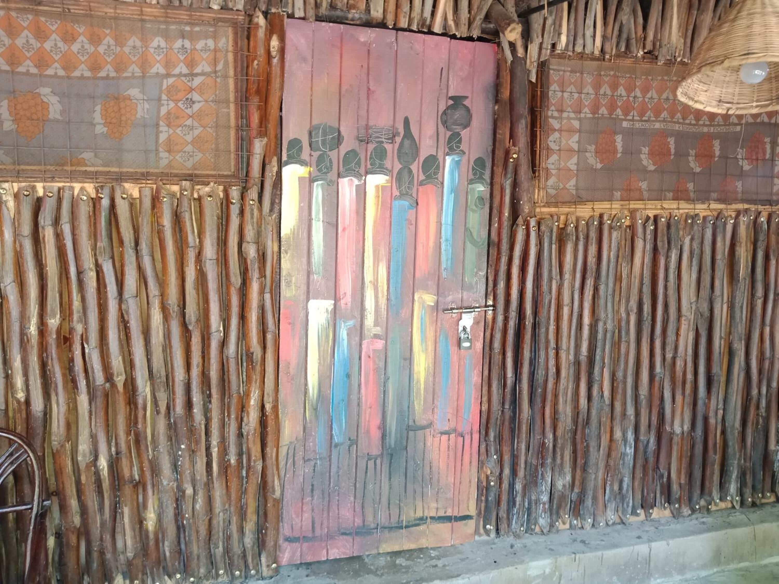 Una habitación rústica con una puerta de madera, adornada con alegres jarrones pintados y un techo tejido.