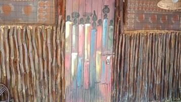 Una habitación rústica con una puerta de madera, adornada con alegres jarrones pintados y un techo tejido.