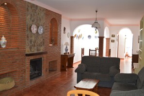 A living room with a brick fireplace, a sofa, and a dining area with a table and chairs.