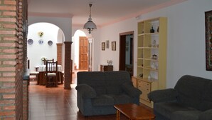 A living room with two sofas, a wooden coffee table, and a bookshelf. There is a dining area with a table and chairs in the background. - Villa Remedios, whole house located in rural environment. (Málaga)