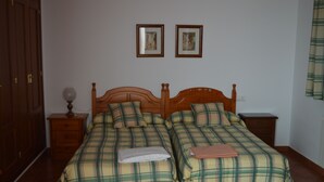 A room with two beds, wooden headboards, a nightstand with a lamp, and two framed pictures on the wall. - Villa Remedios, whole house located in rural environment. (Málaga)