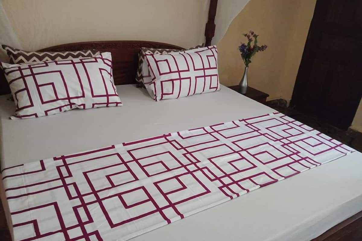 Una cama bien hecha con una colcha de diseño geométrico y almohadas a juego.