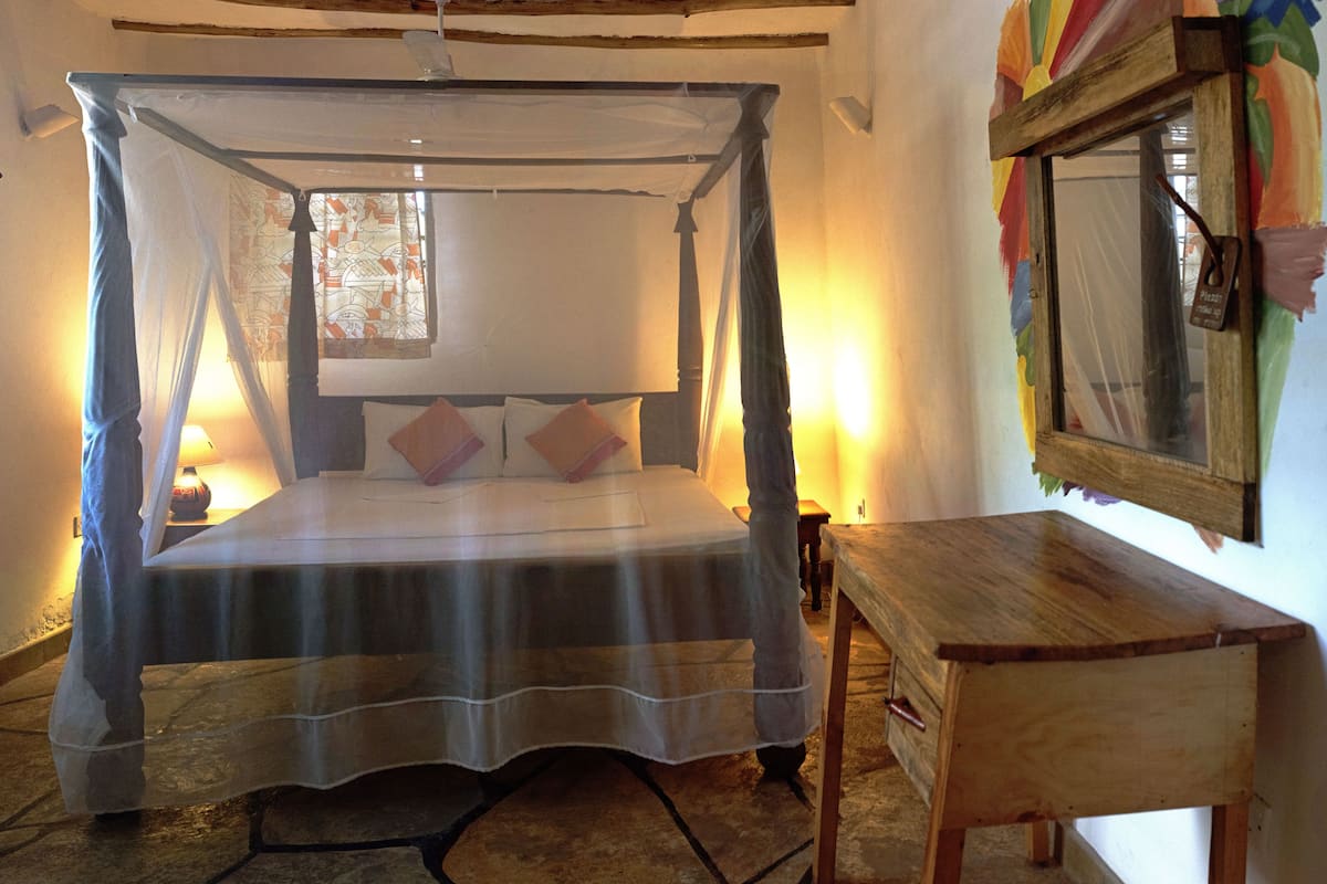 Una cama con dosel, una mesita de noche y un espejo en la pared.