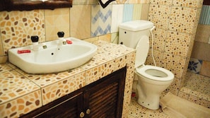 A bathroom with a sink, toilet, and patterned tiles. - Soul breeze Beach Resort (Diani Beach)