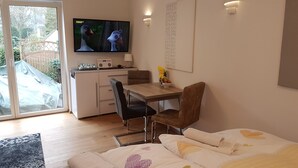 A cozy room with a TV displaying animated characters, a dining area with a table and chairs, and a bed with a heart-patterned duvet. - Luxusapartment Steinbreche (Bergisch Gladbach)