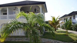 A two-story building with a balcony, surrounded by a well-maintained lawn and palm trees. - Morning Star Diani (Diani Beach)