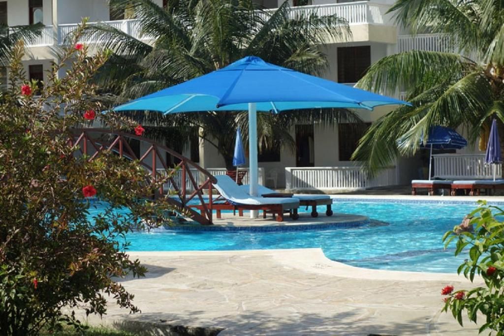 A swimming pool with lounge chairs and a blue umbrella.