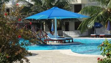A swimming pool with lounge chairs and a blue umbrella.