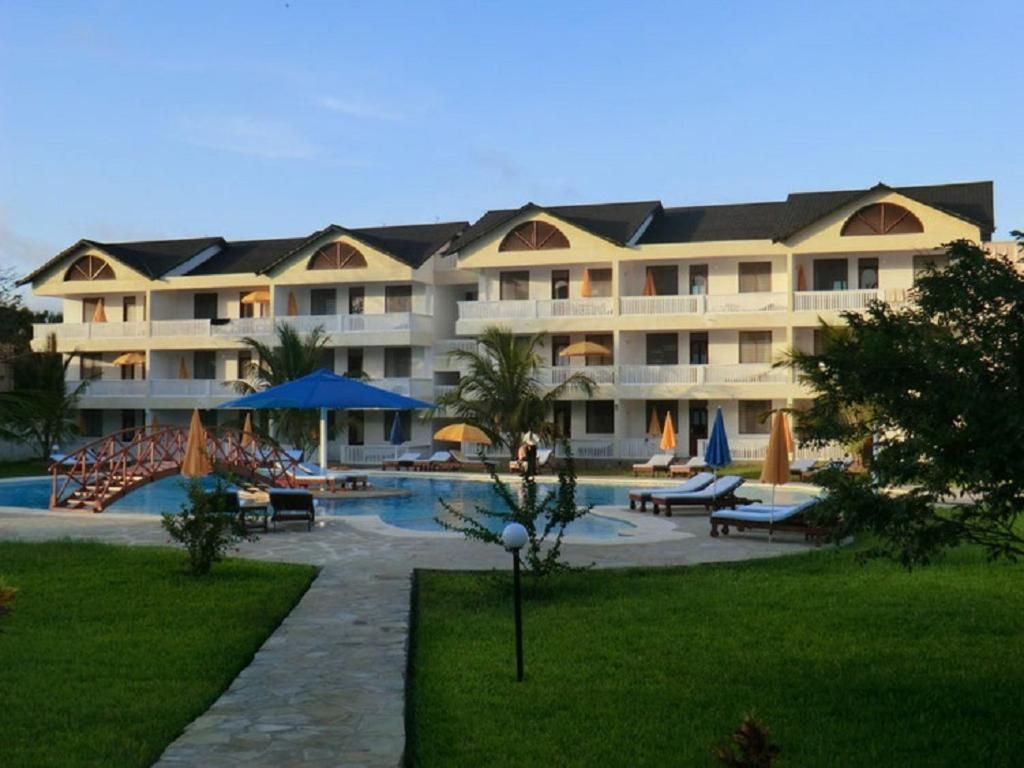 A hotel with multiple balconies, a swimming pool, and sun loungers.