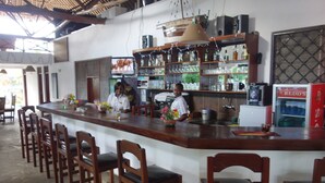 A bar area with wooden chairs, a counter, and a refrigerator. - Morning Star Diani (Diani Beach)