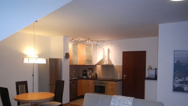 A compact living space with a dining area, kitchenette, and a sofa with patterned throw. - Großzügiges Zweiraumapartment Troisdorf (Troisdorf)