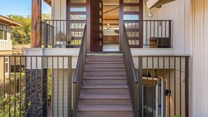 A two-story house with a wooden staircase leading to a balcony. - Stunning 4BR KaMilo Home 349 at Mauna Lani – Relaxed Elegance & Pool/Spa (Kamuela)