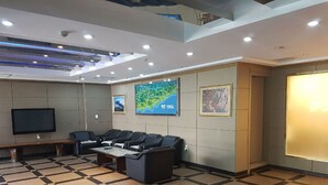 A conference room with a large screen, black leather sofas, a coffee table, and a map on the wall. - Green Resortel (Sokcho)