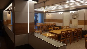 A modern conference room with wooden tables and chairs, recessed ceiling lighting, and a large mirror. - Green Resortel (Sokcho)