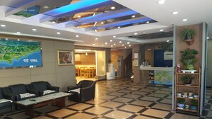 A hotel lobby with a checkered floor, seating area, reception desk, and a map on the wall. - Green Resortel (Sokcho)