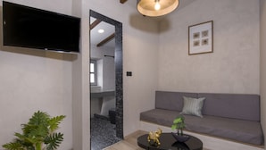 Ein modernes Wohnzimmer mit Flachbildfernseher, einer Couch, einem Couchtisch und einem Topf mit Pflanze.