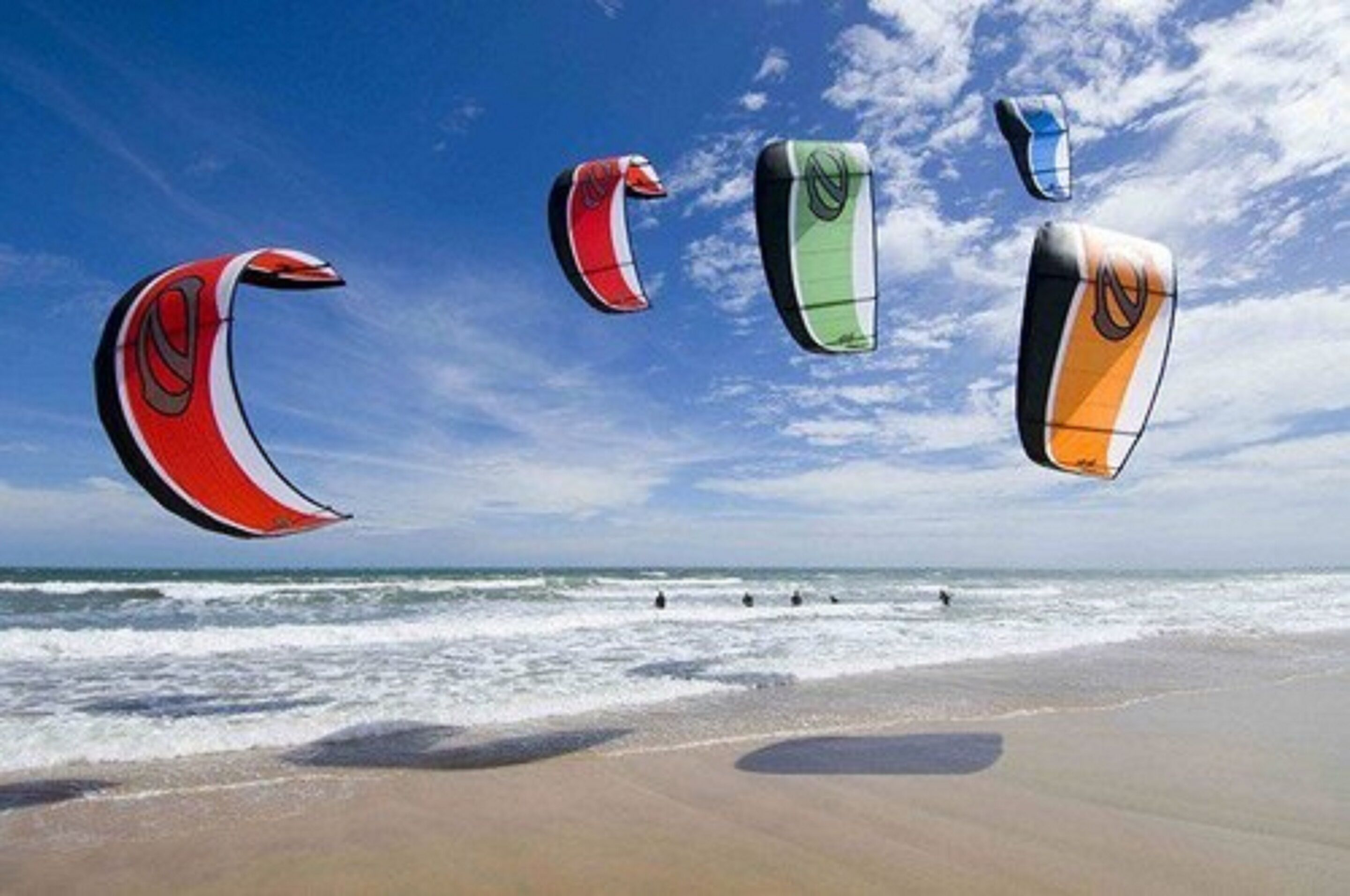 Ein Strand mit mehreren Drachen am Himmel.