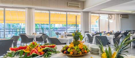 Comedor con mesas dispuestas para una comida, con frutas y adornos de piña.