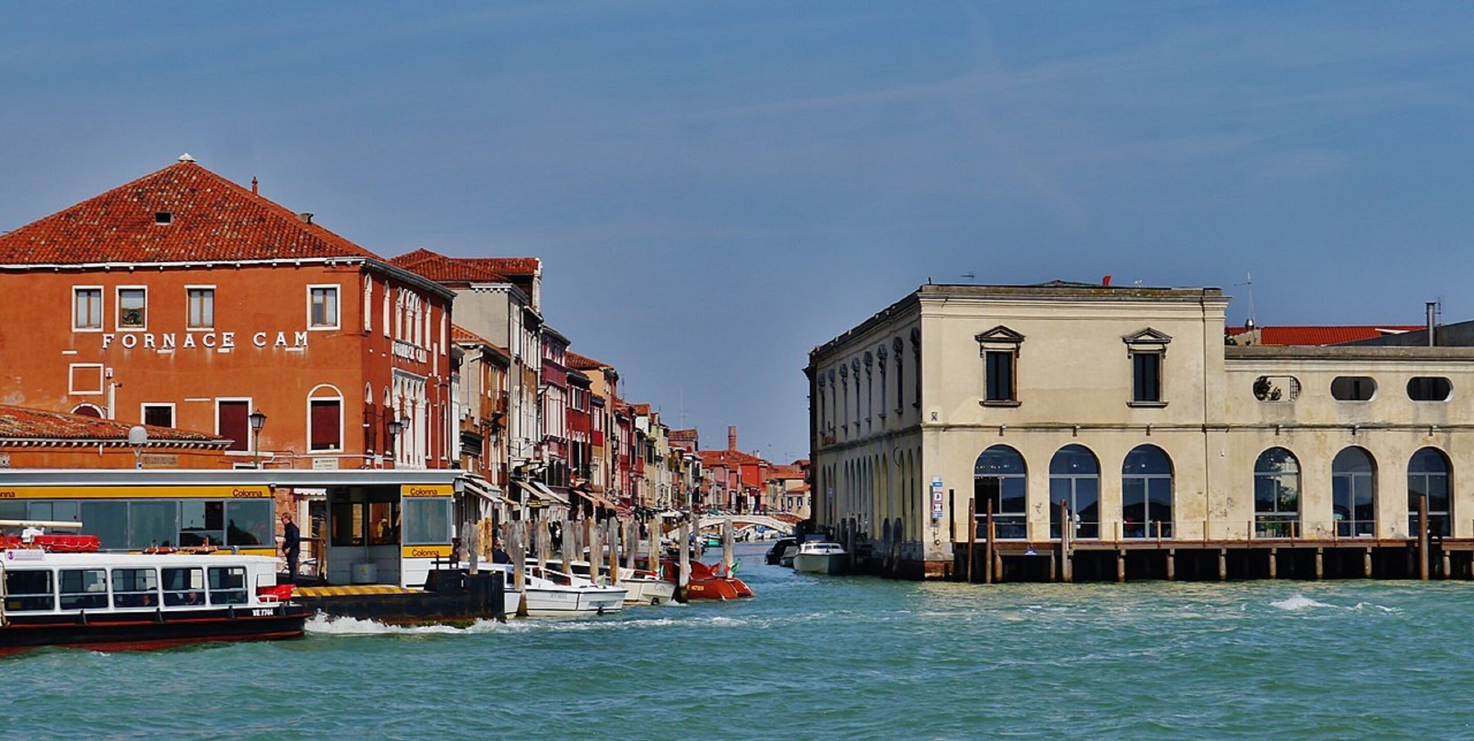 A canal with buildings on either side, a boat, and a bridge in the background.