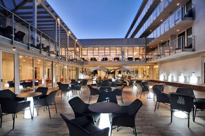 Un espacio interior amplio con varias mesas y sillas, ventanas grandes y un diseño arquitectónico moderno.