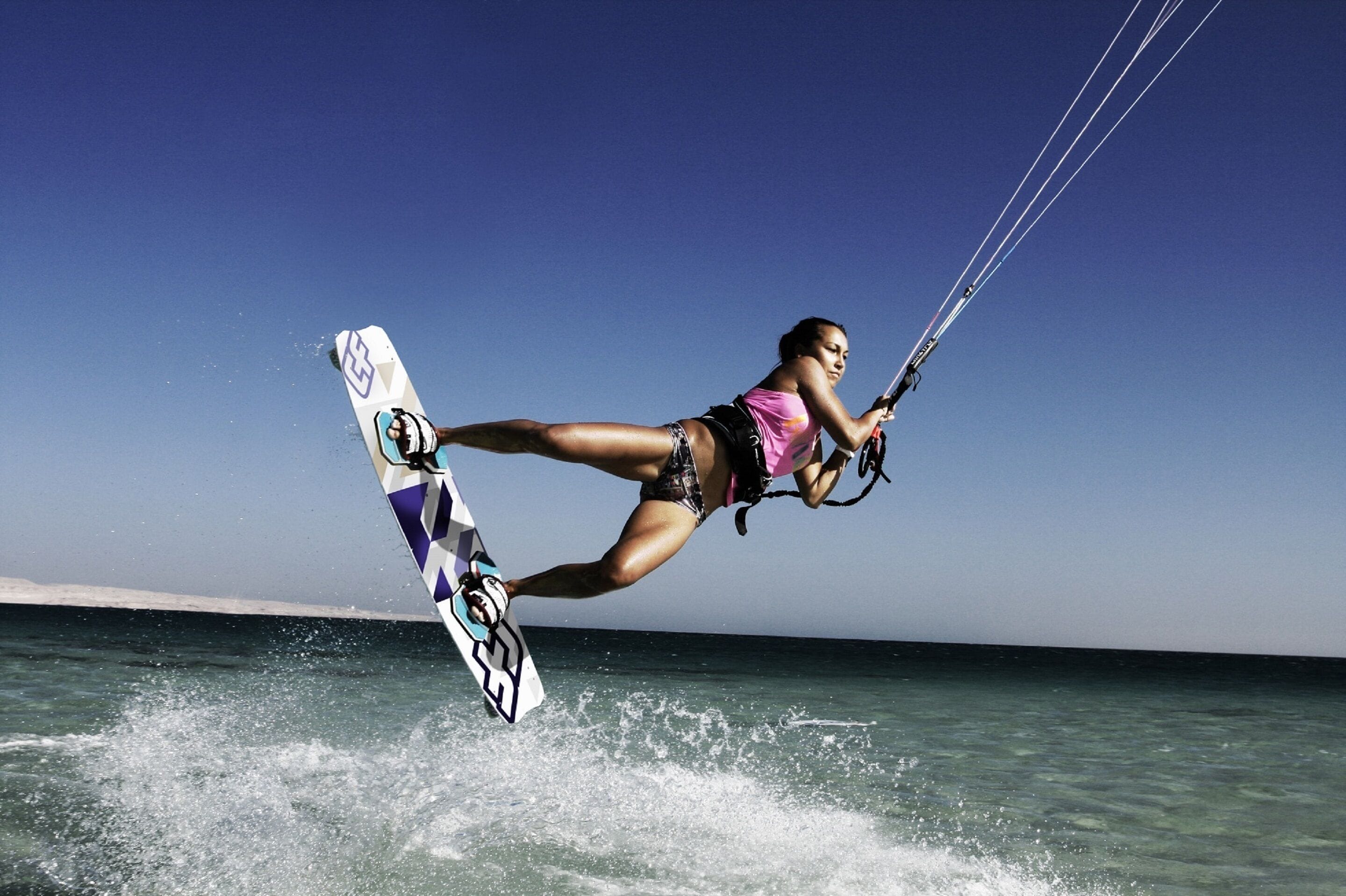 Eine Person beim Kitesurfen über dem Wasser.
