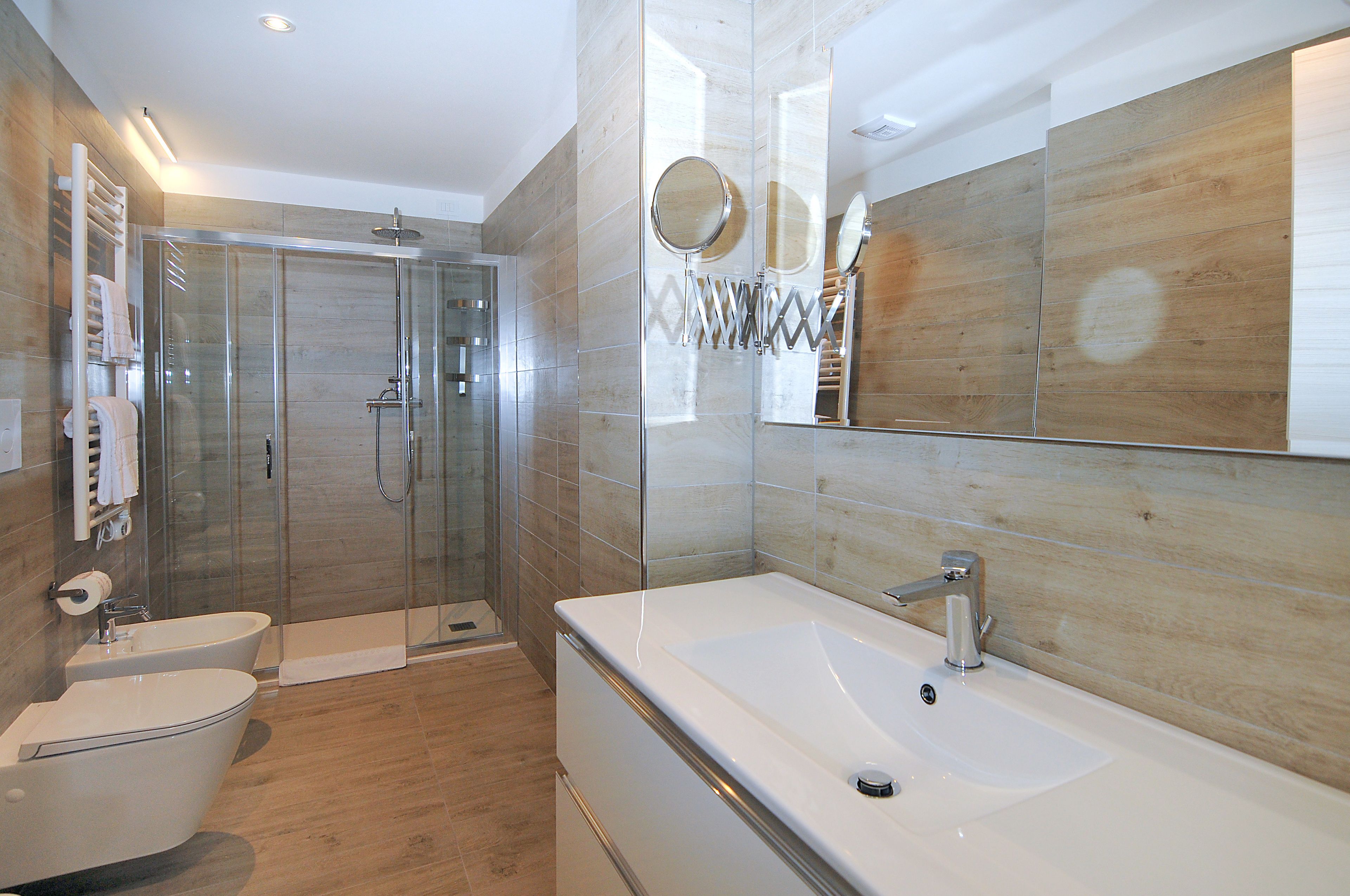 Un baño moderno con cabina de ducha de vidrio, bañera independiente y un espejo grande.