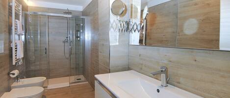 Un baño moderno con cabina de ducha de vidrio, bañera independiente y un espejo grande.