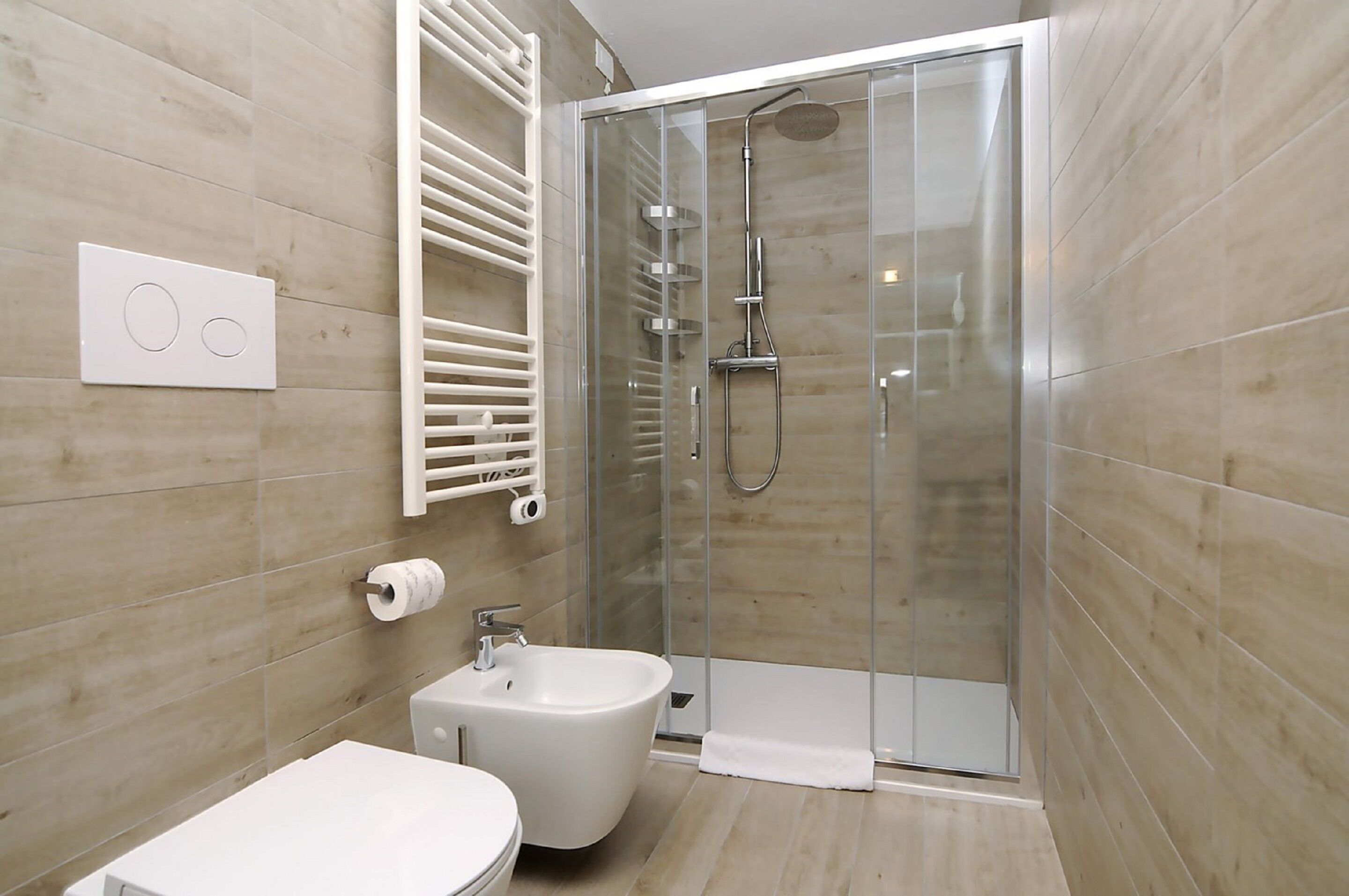 Ein modernes Badezimmer mit einer Duschkabine, einem Bidet und einer Toilette.