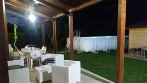 An outdoor patio area with white wicker furniture, a table, and chairs. There is a pool in the background. - Country house with pool, renovated and well furnished (San Lorenzo)