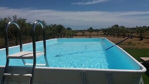 A rectangular swimming pool with a ladder on one side, surrounded by a grassy area and trees. - Country house with pool, renovated and well furnished (San Lorenzo)