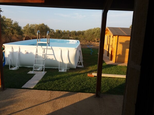 An above-ground swimming pool with a ladder, surrounded by a grassy yard and a wooden building. - Country house with pool, renovated and well furnished (San Lorenzo)