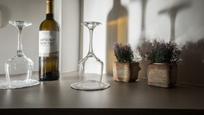 Una botella de vino, dos copas de vino y dos plantas en macetas sobre una mesa.