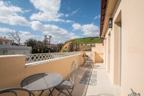 A balcony with a table and chairs, a tiled floor, and a view of a hill and buildings in the distance. - Cretan Berry Portou (Chania)