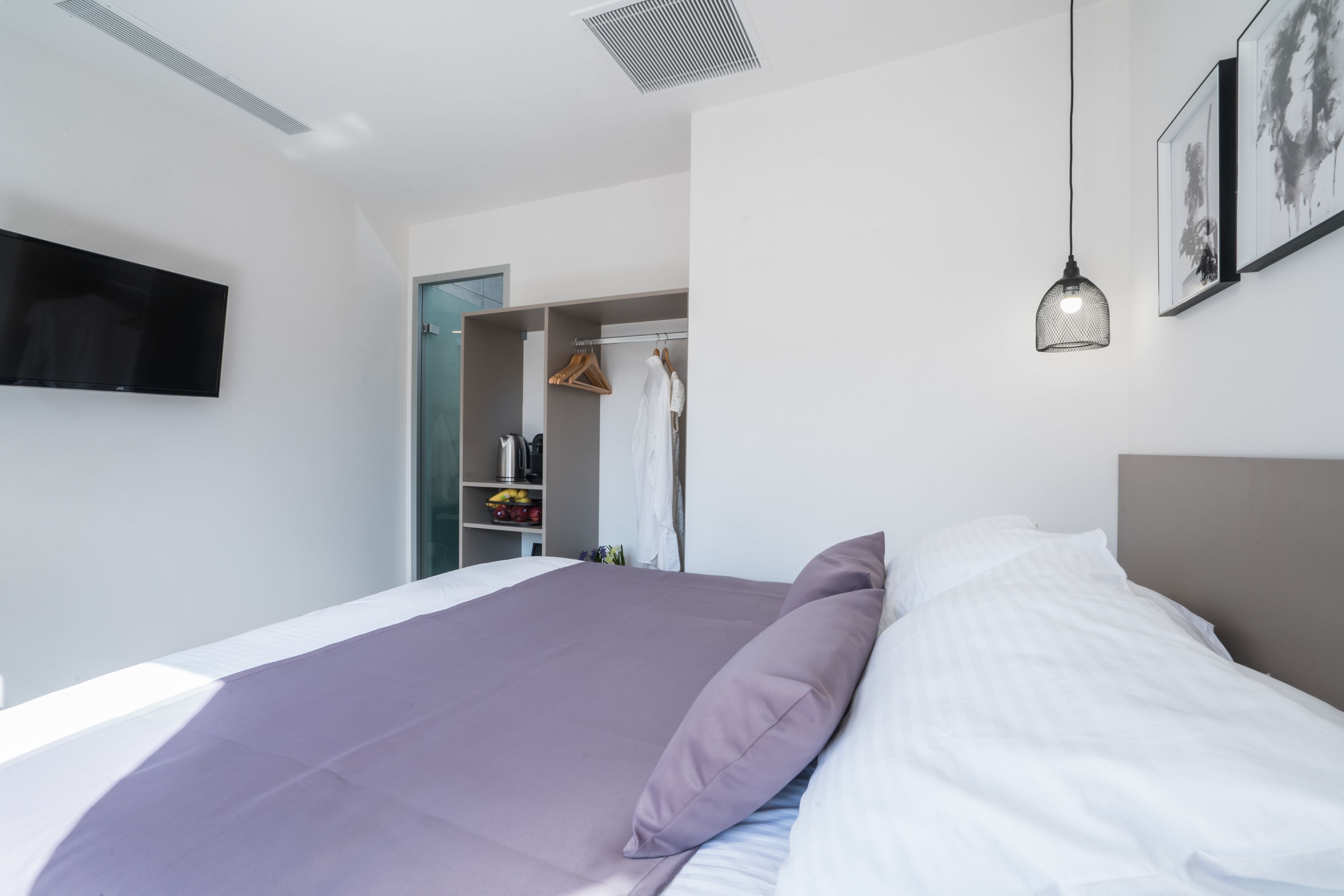 Un dormitorio moderno con una cama grande, un armario y un televisor montado en la pared.