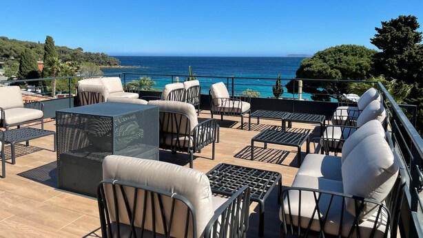 Un patio al aire libre con mobiliario y vista al mar.