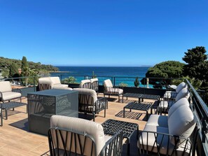Un patio al aire libre con mobiliario y vista al mar.