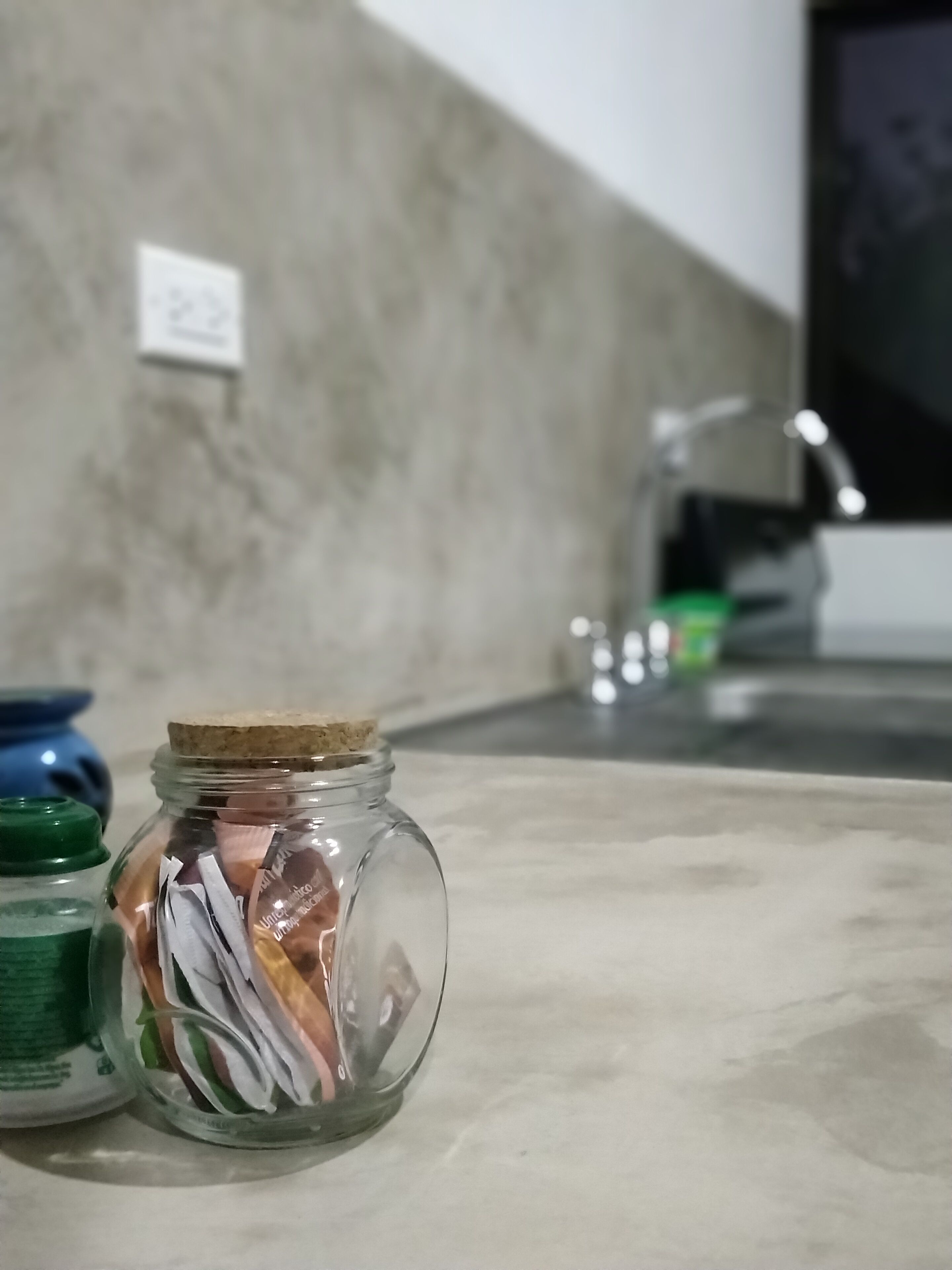 A kitchen counter with a glass jar containing food items, a blue container, and a green container.