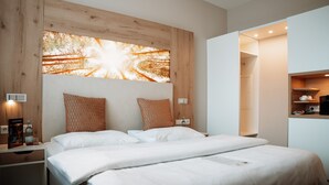 Quarto de hotel moderno com uma cama grande, cabeceira de madeira e uma obra de arte na parede.