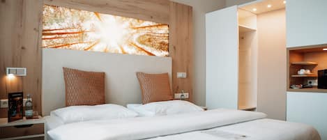 A modern hotel room with a large bed, wooden headboard, and a wall-mounted artwork.