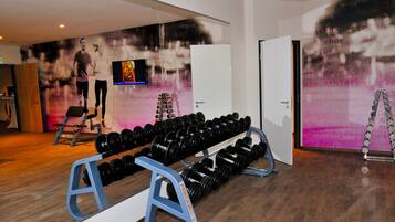 A gym with exercise equipment, a television, and motivational posters on the wall.
