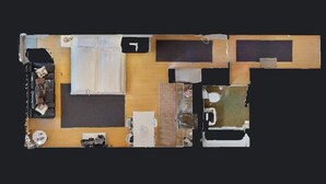 Ein Grundriss eines Hotelzimmers mit Bett, Schreibtisch, Stuhl und einer kleinen Sitzecke.
