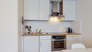 Eine kompakte Küche mit Edelstahlbackofen, eingebautem Geschirrspüler und Spüle.