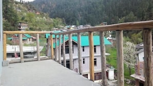 A view of a mountainous area with traditional houses and a wooden railing. - Jibhi Cottage (Banjar)