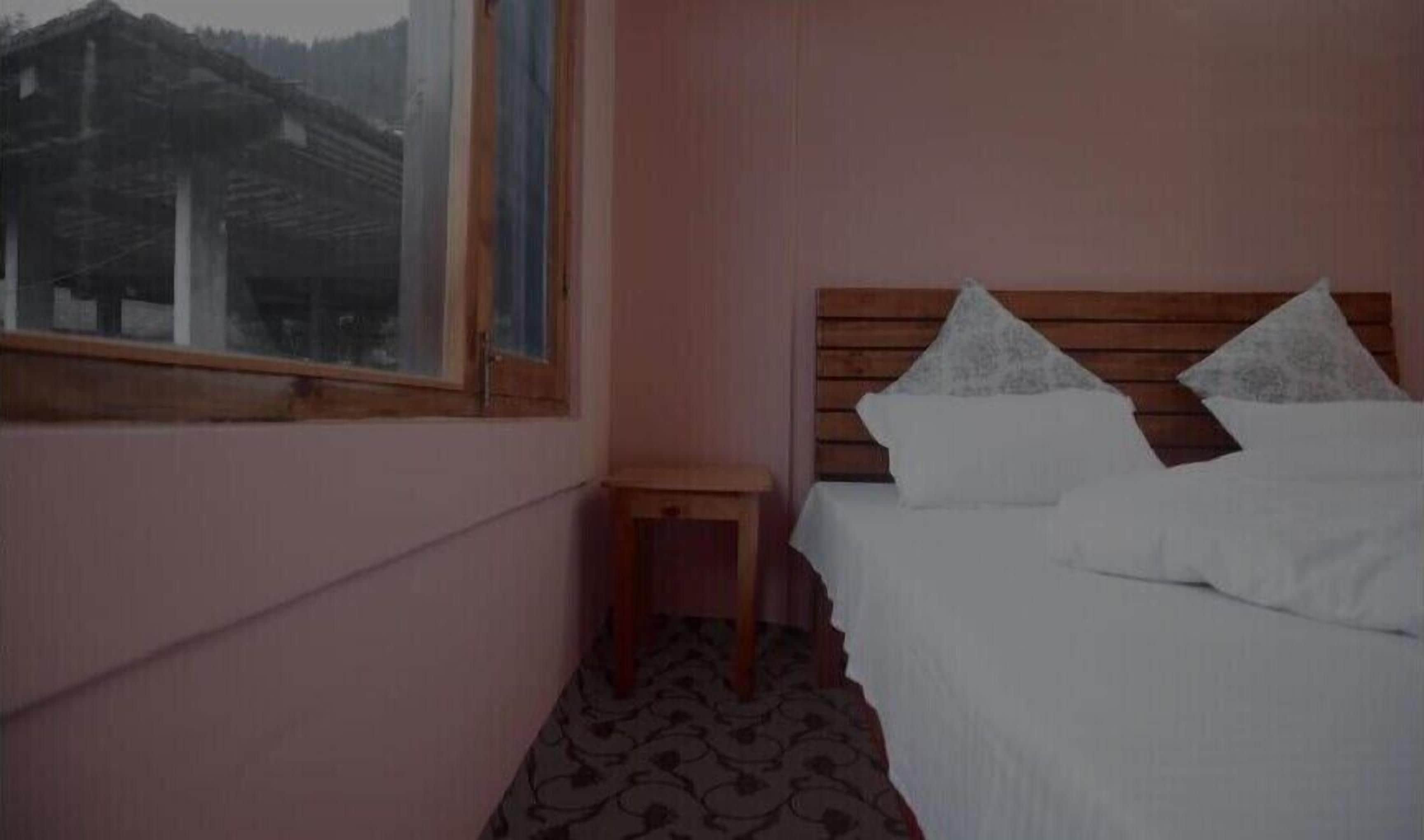 Ein Schlafzimmer mit einem hölzernen Kopfende, einem kleinen Nachttisch und einem Fenster mit Blick auf ein Gebäude.