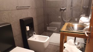 Un baño pequeño con inodoro, bidé y ducha.